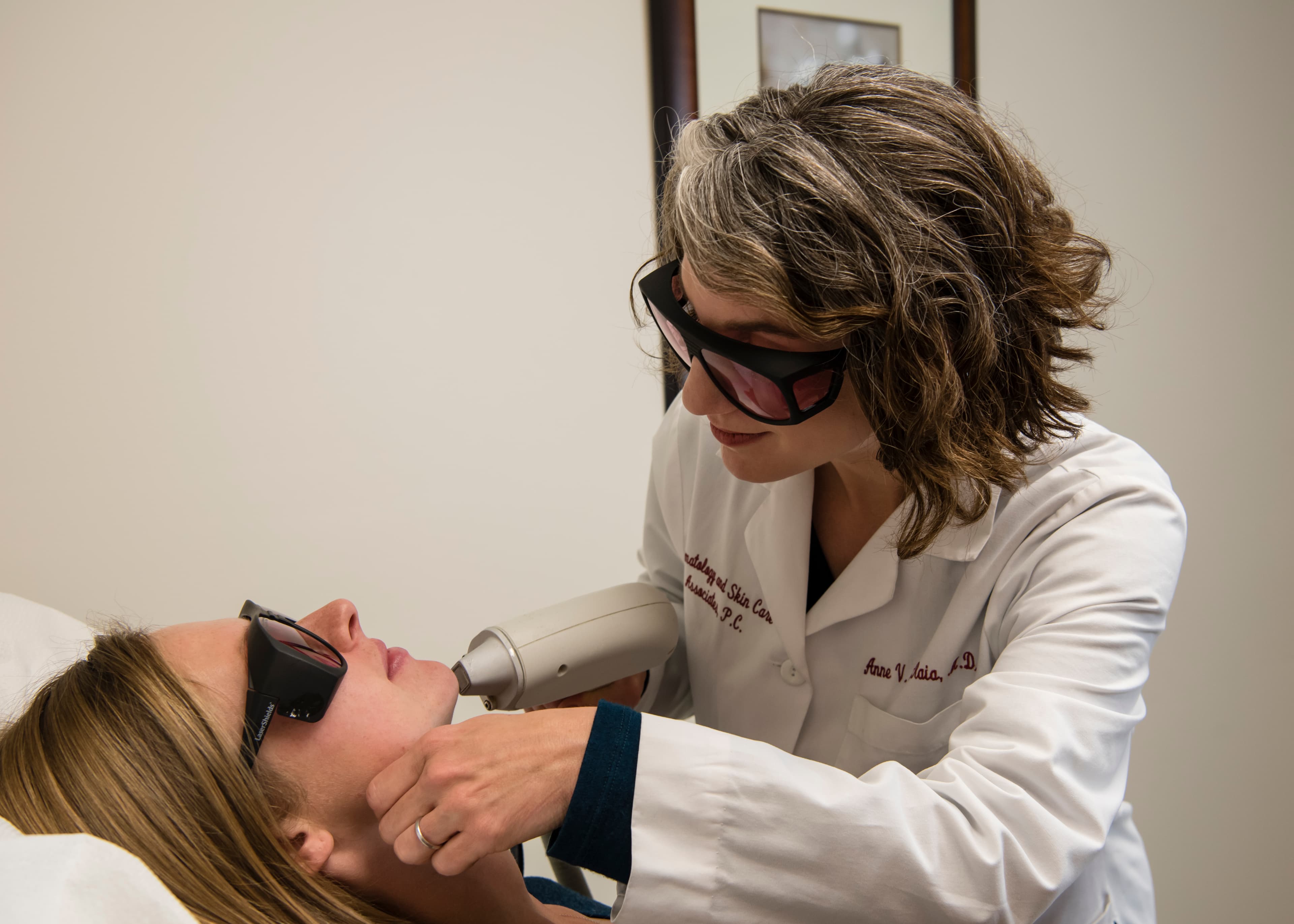 Dr. Anne Maiorana performing a laser treatment on a patient, both wearing protective laser glasses