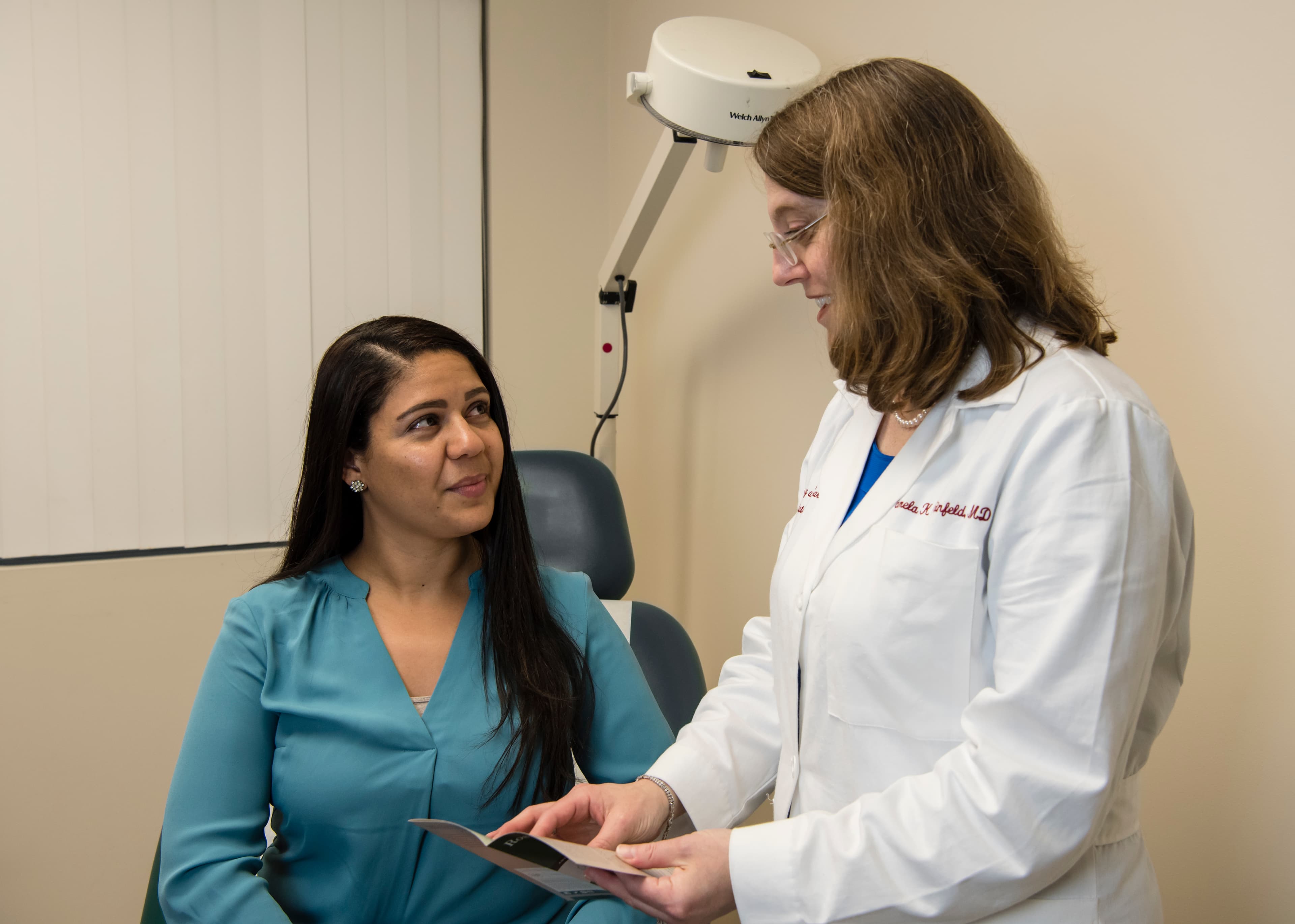Dr. Pamela Weinfeld in white coat consulting with a patient at Dermatology and Skin Care Associates