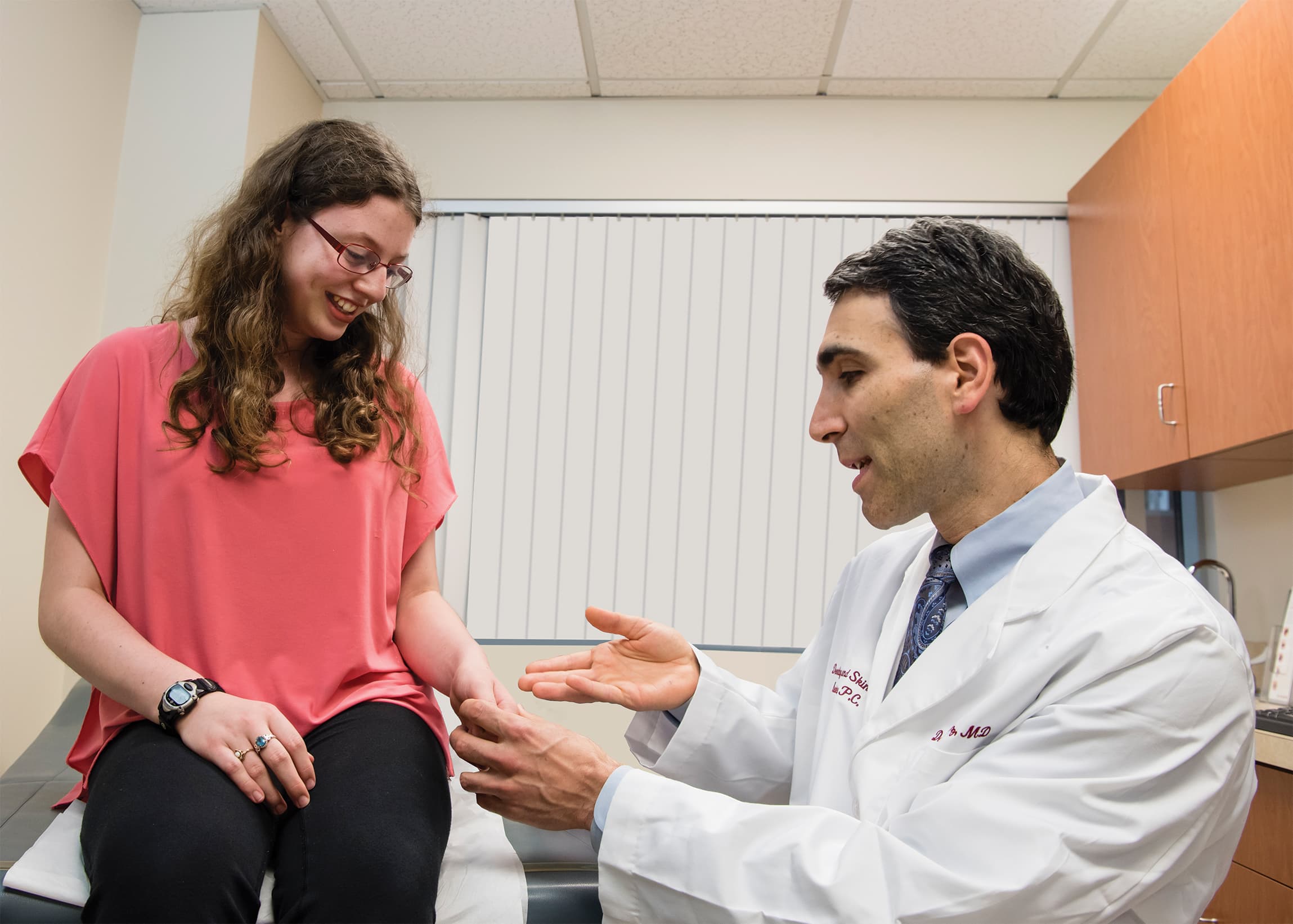 A physician examining a young patient's wrist during a pediatric dermatology visit